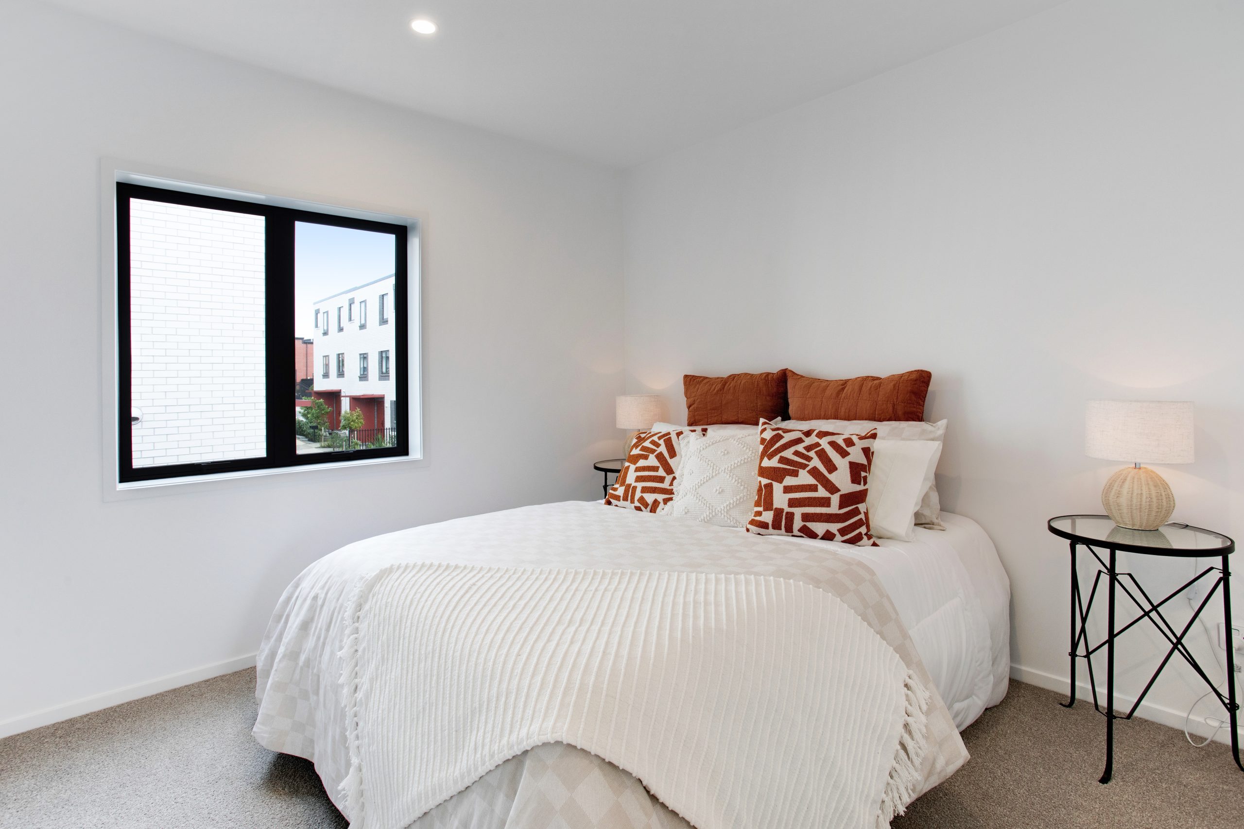 Bedroom #2, staged with white duvet and burnt orange pillows